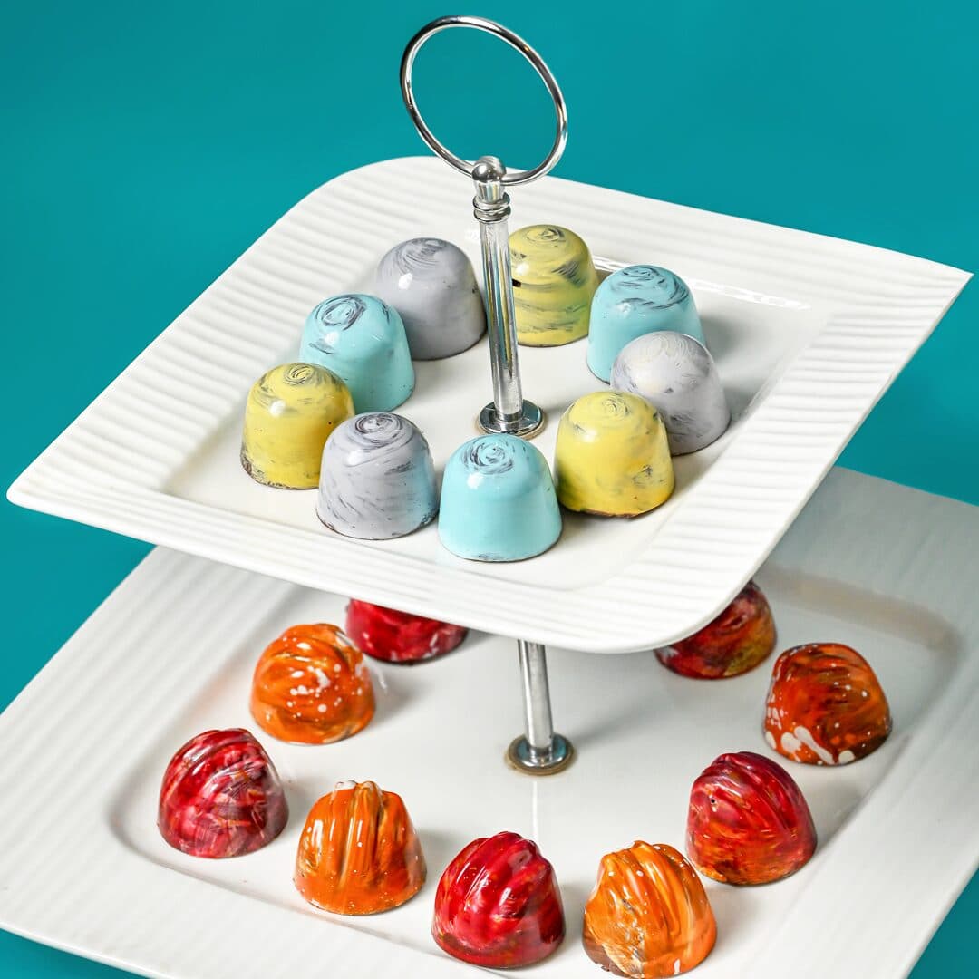 Hand-painted artisanal chocolates on a two-tier cake stand